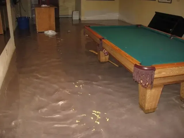 Standing water spread across a finished basement rec room