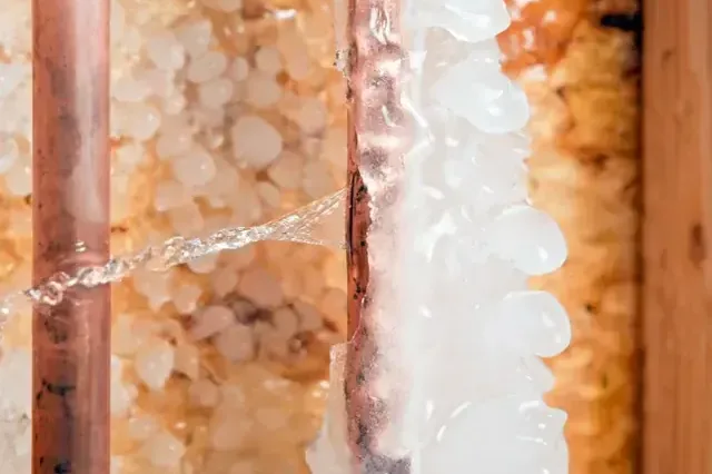 Ice coating a copper supply pipe inside an insulated wall cavity