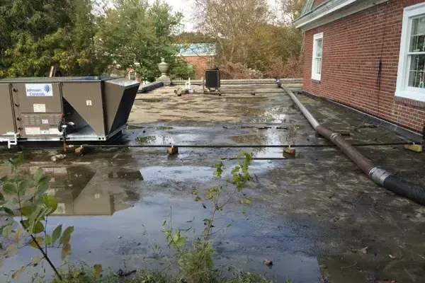 Rainwater ponding around a rooftop HVAC unit on a flat roof