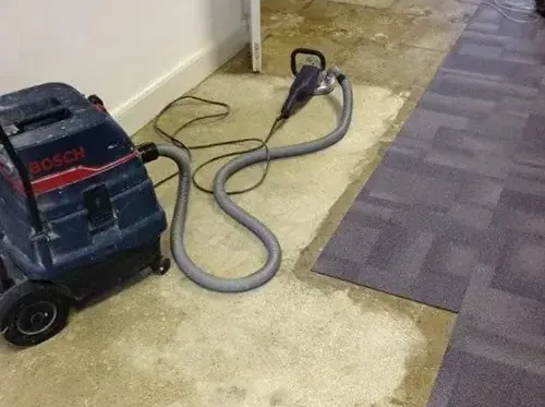 Portable extractor and wand pulling water out of soaked carpet tiles